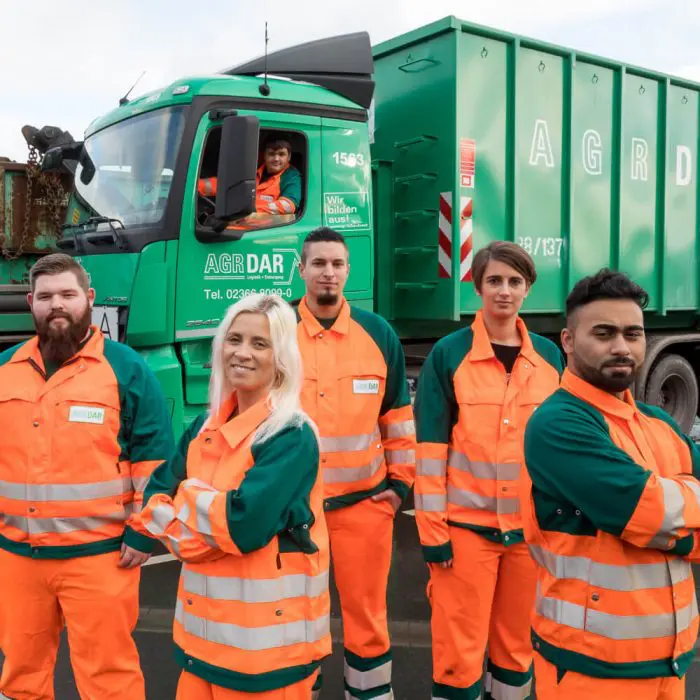 Gruppe von AGR Mitarbeitern stehen vor einem LKW in Arbeitsuniform.