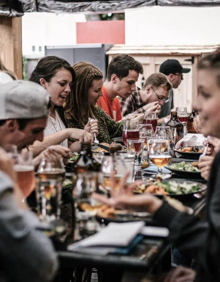 Gruppe von Leuten die gemeinsam am Tisch sitzen und essen.