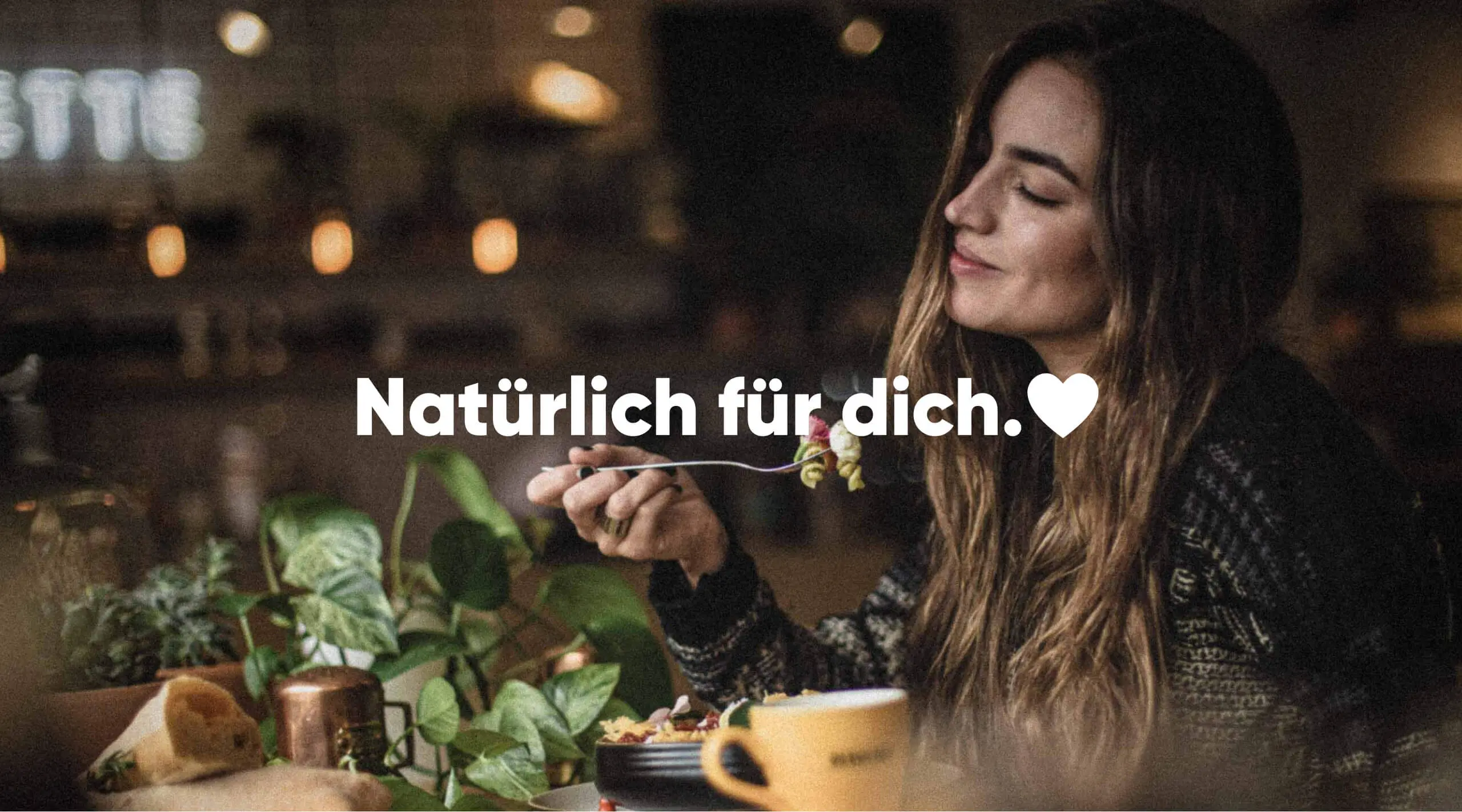 Foto einer Frau beim gesunden Essen mit einer Gabel in der Hand und dem Schriftzug "Natürlich für dich." auf dem Bild.