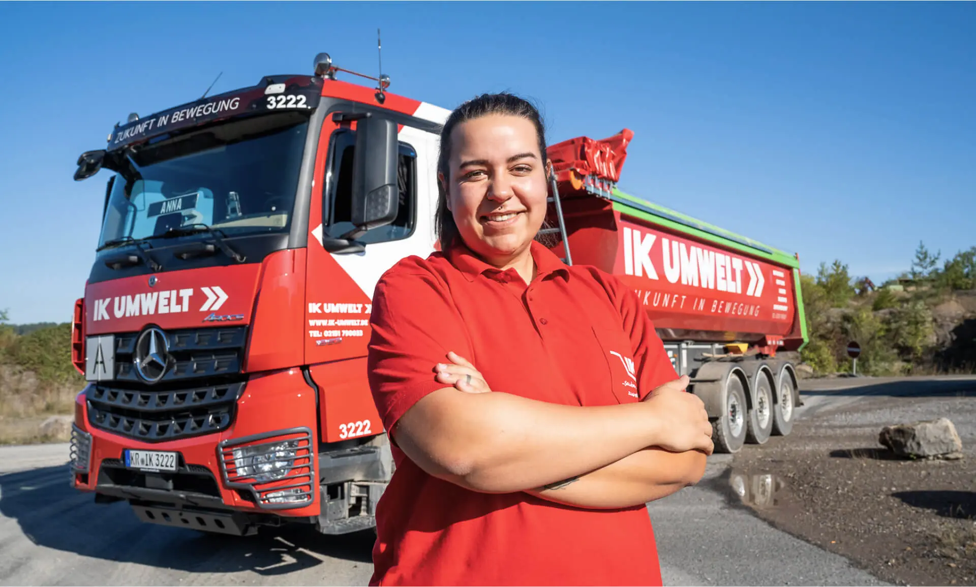 Mitarbeiterin von IK Umwelt steht vor einem großen LKW mit Arbeitskleidung.