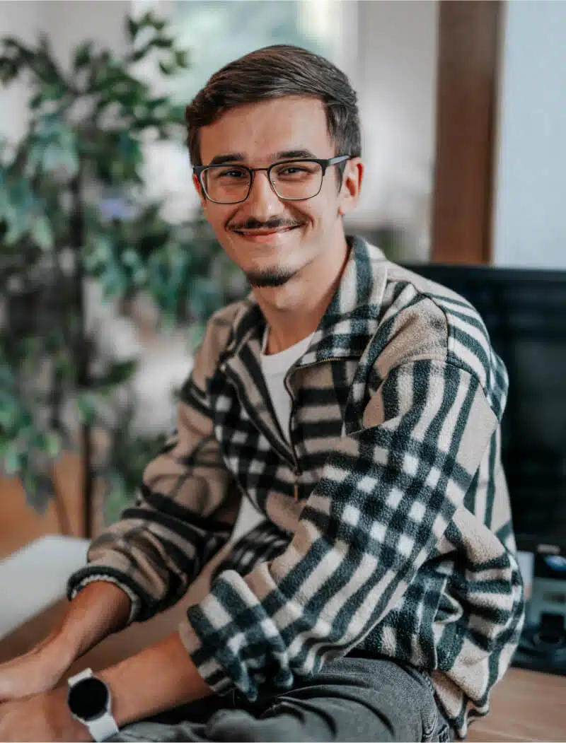 Portrait von Gabriel der auf einem Tisch sitzt und in die Kamera schaut.