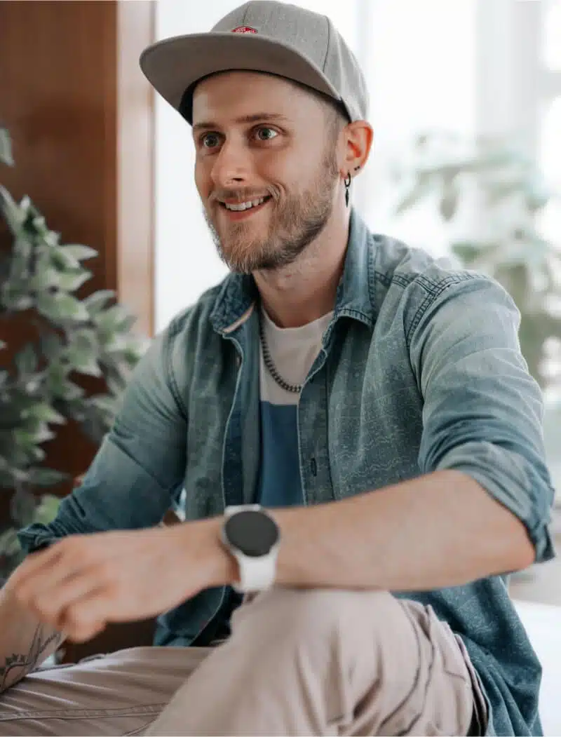 Portrait von Tobi, der auf einem Tisch sitzt und lacht.